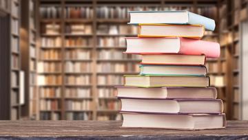 Pila di libri su un tavola di una biblioteca © Billion Photos/Shutterstock